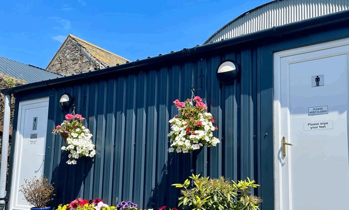 shower and toilet block with beautiful hanging baskets and planter in full bloom